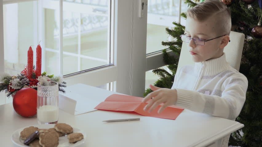 Boy fold the letter to Santa and puts inside envelope | Shutterstock HD Video #1011864056