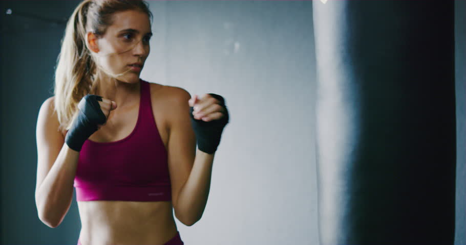 Beautiful athletic woman kickboxing, training with punching bag in the gym, slow motion | Shutterstock HD Video #1011864491