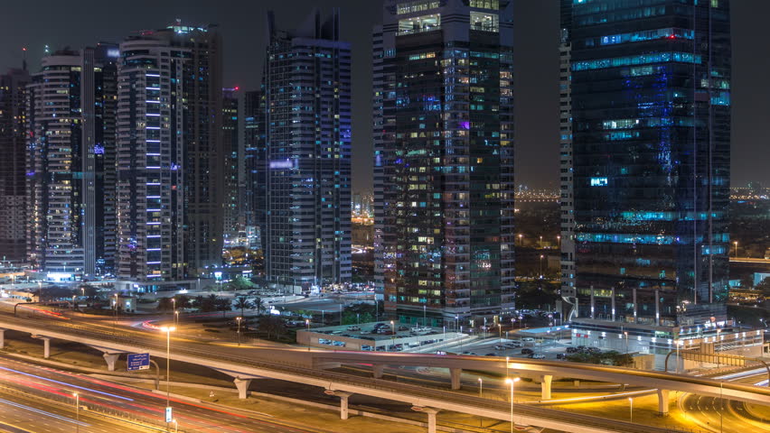 Aerial view of Jumeirah lakes towers with illuminated skyscrapers night timelapse with traffic on sheikh zayed road and metro line. Rooftop view from Dubai marina | Shutterstock HD Video #1011865187