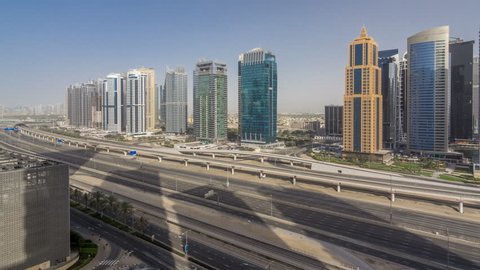 Aerial view of Jumeirah lakes towers skyscrapers timelapse with traffic on sheikh zayed road and metro line. Sunset time with long shadows and reflections on a glass