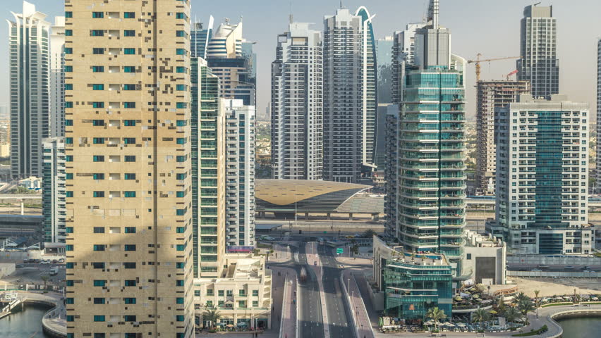 Amazing colorful dubai marina and JLT skyline during sunset timelapse. Great perspective of multiple tallest skyscrapers of the world with metro station. Sunlight over buildings. United Arab Emirates.