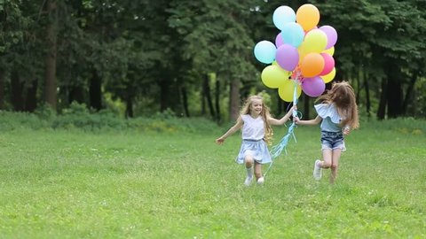 two sisters walking in a park with balloons