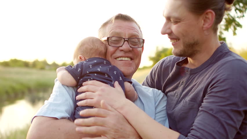 A happy young man hugs his father and newborn son. Father's love. the continuity of generations. Male tenderness. Fathers Day | Shutterstock HD Video #1011892064