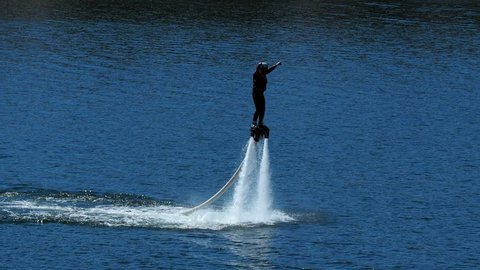 man is riding a flyboard on summer vacation lake, Tallinn. Flyboard is a aerial machine for personal watercraft which allows propulsion underwater. Positive human emotions, feelings, joy.  new sport