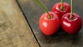 Rotating cherry fruits on wooden table surface.