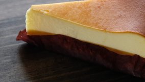 Rotating slice of cheese cake on wooden table