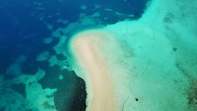 Aerial drone bird's eye view video of tropical caribbean island forming atoll with small sandy beach and beautiful emerald and sapphire clear waters