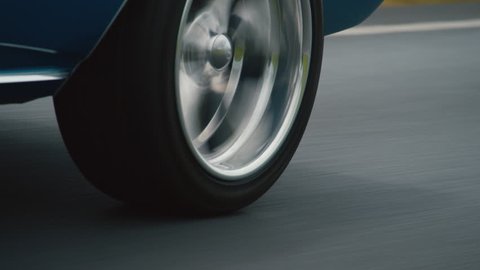 Close up of back wheel blue car driving on road in daylight
