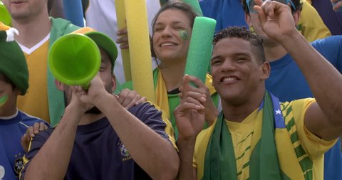 Brazilian football fans dancing and cheering at football match, slow motion