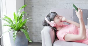 woman lying on sofa and listen music happily