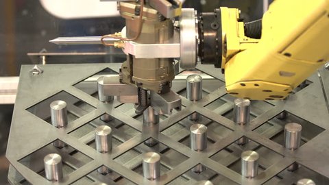 Yellow robotic arm arranges metal elements after being produced. Automatic industrial machinery equipment.
