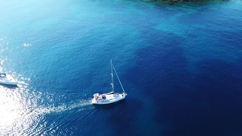 Aerial drone bird's eye view video of luxury yacht cruising in bay below archaeological site of Cape Sounio, Temple of Poseidon, Attica, Greece