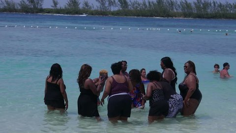 Group of African American women standing in the sea talking, taking selfies and having fun - Nassau Bahamas September 2017