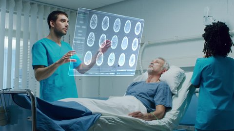 Futuristic Medical Ward with Sick Patient Lying in Bed and Doctor using Gestures and Augmented Reality Interface. Doctor Looks at Brain Scans and Medical History of the Patient. Shot on RED EPIC-W 8K.