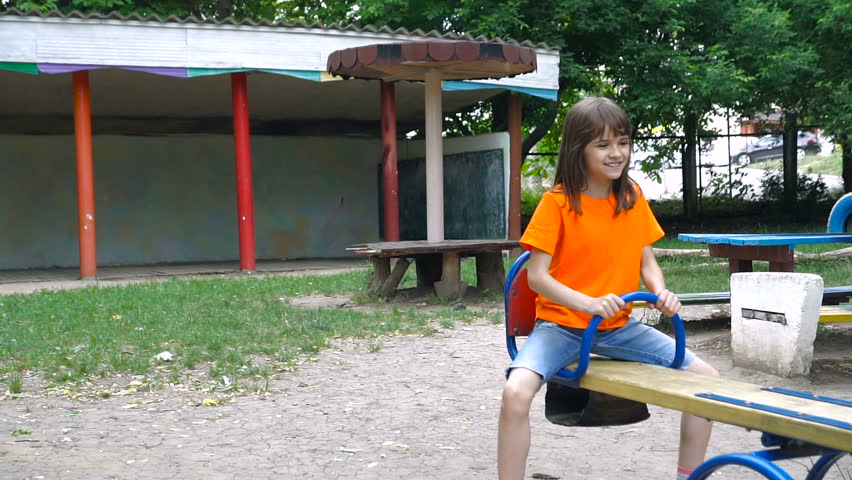 Happy two children ride on a swing at summer park. Cute teen girl swings at playground outdoors.