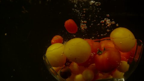Glass bowl with tomatoes falling in water, Ultra Slow Motion