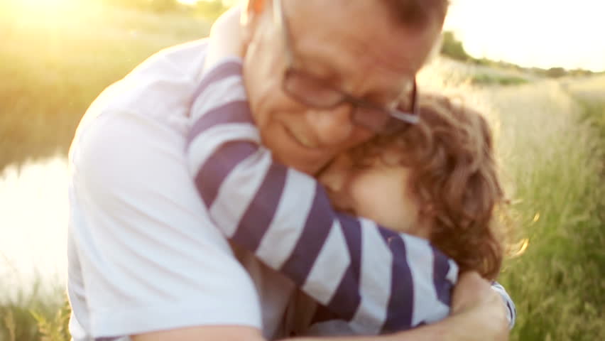 Closeup portrait of a mature man hugging his late son. Happy fatherhood. Curly child, a man wearing optical glasses. Colorful sunset Royalty-Free Stock Footage #1011945614