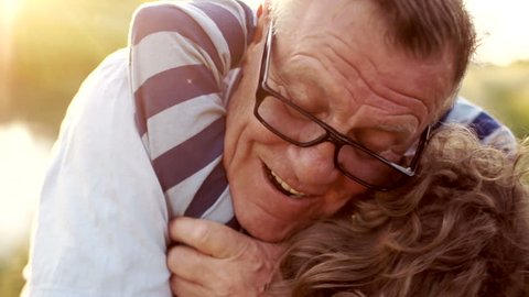 Closeup portrait of a mature man hugging his late son. Happy fatherhood. Curly child, a man wearing optical glasses. Colorful sunset