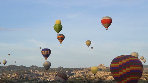Lots of hot air balloons flying over valleys in Goreme, Turkey. Tourists from all over the world come to Cappadocia to make a trip in a hot-air balloons.