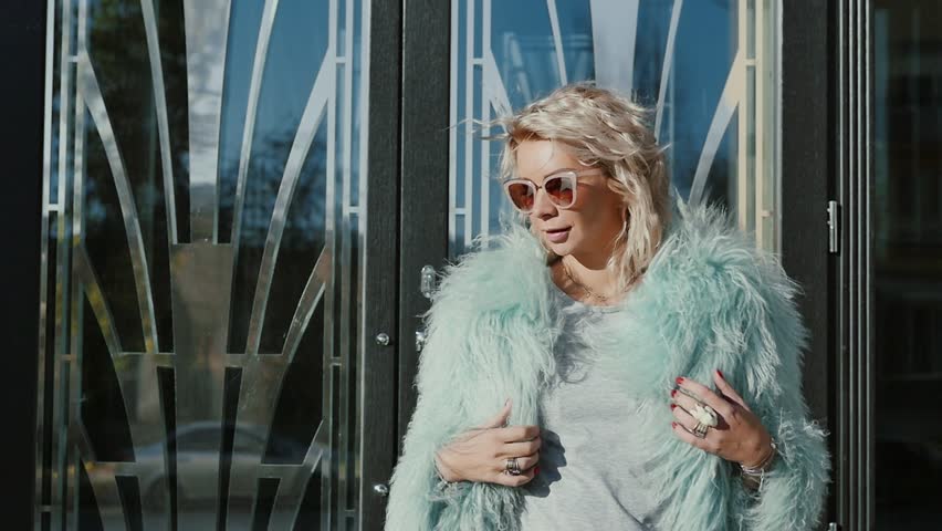 young woman in the glasses is walking near the business center in the evening. The girl looks around the place.