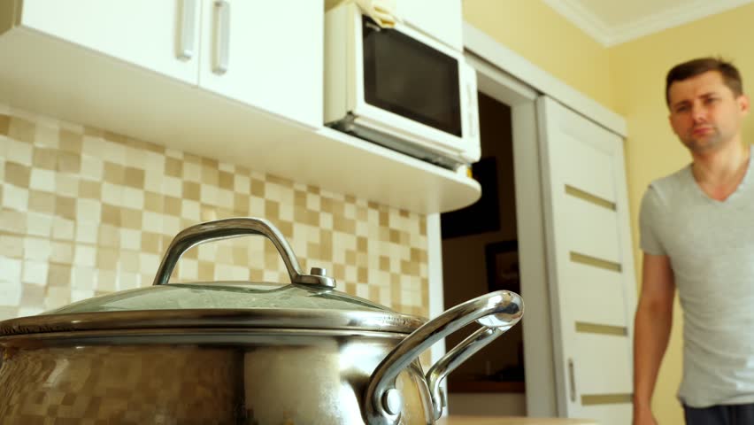 Man is cooking in the kitchen. Open pan with boiled water.