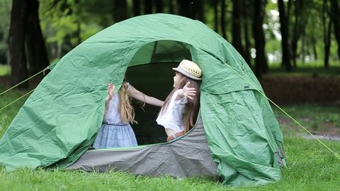 Two little girls are playing in a tent in the park