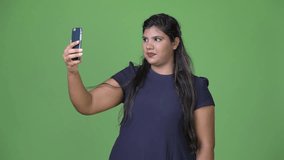 Young overweight beautiful Indian businesswoman against green background