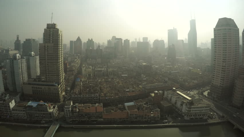 Smoggy Shanghai skyline day time-lapse. A pollution filled Chinese city suffering thick smog, causing poor vision and glare in an urban. Overlooking the Suzhou river and hutongs, old neighborhoods.