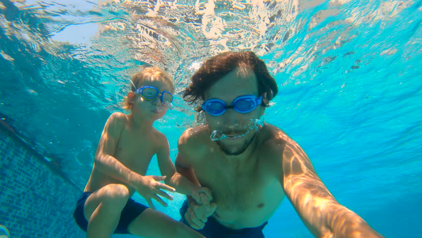 Slowmotion underwater shot of father and his toddler son swining diving and having fun in a pool | Shutterstock HD Video #1011966437