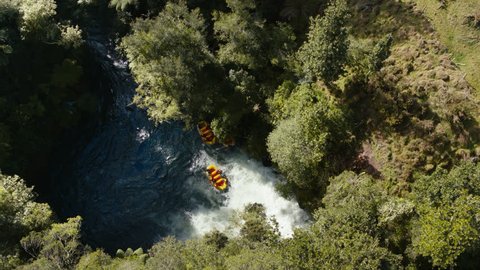 Drone shot rafting on the Kaituna river in Rotorua, New Zealand. Yellow inflatable boat surrounded by green trees.