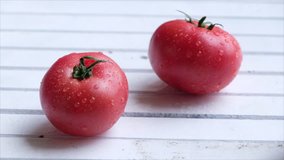 Tomato fruits rolling on white table top.
