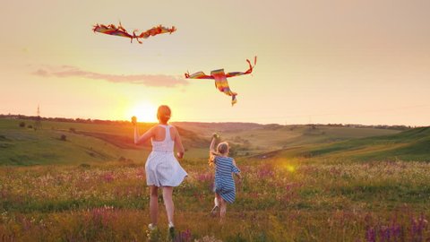 Mom and daughter together launch kites. In a picturesque place at sunset. Happy family concept