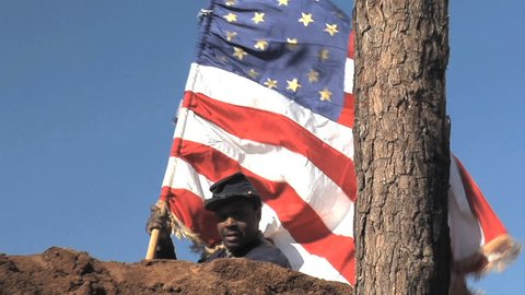 VIRGINIA - JUNE 2017 - Reenactment - Civil War 54th Massachusetts Black Soldier stands tall on earthworks with U.S. Flag after battle. "Glory" movie.  African-American military history. Heroic