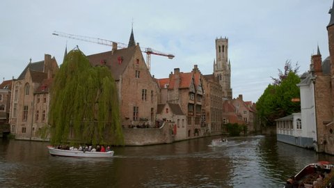 BRUGES/BELGIUM 27th APRIL 2018: Static shot of Dijver Canal and Bruges Belfry as tour boats sail past. Taken on an overcast spring day