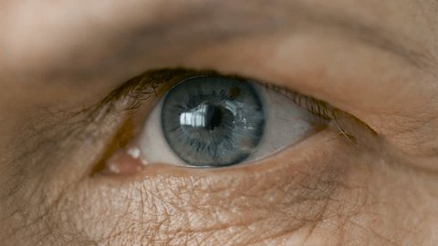 vision and old people concept - close up of blinking senior woman eye
