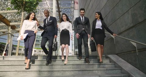 A group of business people of different ethnicities dressed in suits and ties walks proudly after leaving the offices. Concept of: team, success, connection and internationality.
