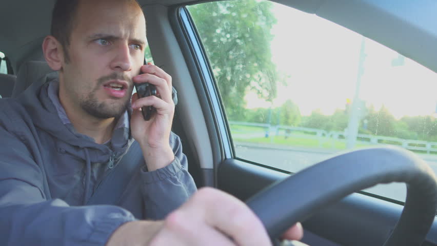 Irresponsible man driving car and speaking on mobile phone