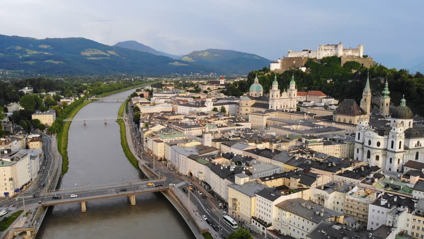 Aerial panoramic view of cityscape of Salzburg city, Salzach River, Salzburg Cathedral, old historic Fortress Hohensalzburg and Alps mountains in backgroung - landscape of Austria from above, Europe