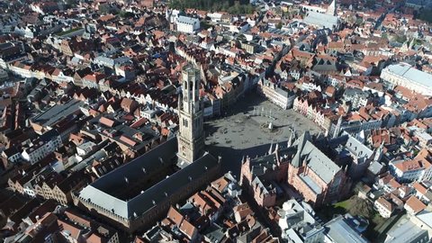 Aerial of Belfry of Bruges in Dutch Belfort van Brugge is a medieval bell tower in the centre of Bruges Belgium and one of the citys most prominent symbols also showing market square in background 4k