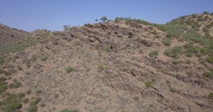 4K high quality aerial summer video of African savanna and riverbed surrounded by bush covered hills in Daan Viljoen National Reserve in Khomas Hochland area near Windhoek, Namibia's capital, Africa