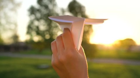 Hand launches paper airplane against sunset background. Slow motion Arkivvideo