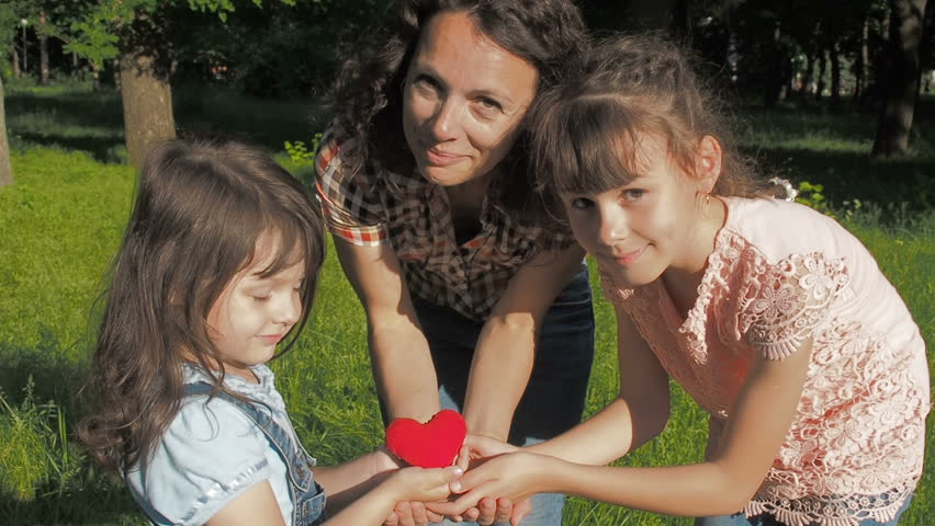 A happy family is holding a heart. Mother and children are holding a heart.