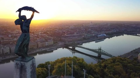 Budapest, Hungary - 4K aerial view of Statue of Liberty on Gellert Hill, Liberty Bridge and skyline of Budapest at sunrise
