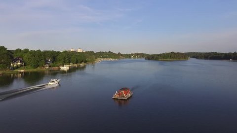 Small House Boat on calm water in summertime. Drone circles around the boat on a beautiful day. people having fun on the boat nicely captured in this aerial shot
