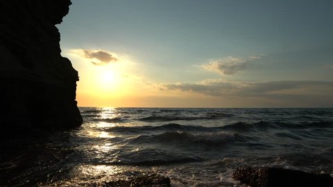 Beautiful sunset in a beach surrounded by rocks in Procida Island, near Naples Napoli, Italy. Sunset on the water.