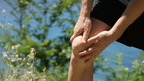 Pain in the knee. Problems with joints. A man is doing a massage. 