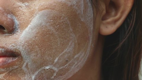 Close up Asia woman cheek. Woman washing face (have wide pores) with white foam by her hand.