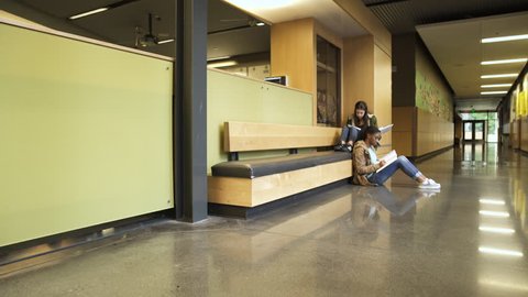 Wide shot of two girls studying on the corridor