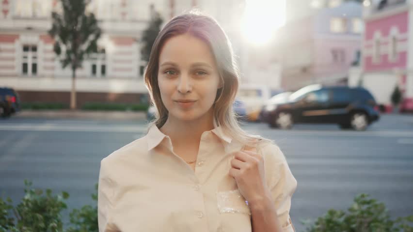 Portrait of a casual student ending classes walking and texting on a mobile phone cars with the university building in the background
