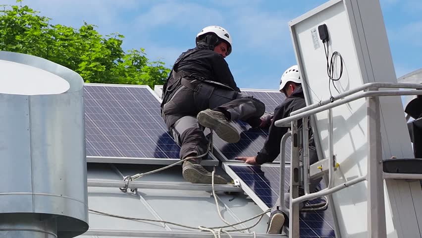 Workers in a protective helmet and a special outfit, install new solar panels on the roof of the house, using a lifting device. Modern solar panels produce clean electricity. Royalty-Free Stock Footage #1012044248